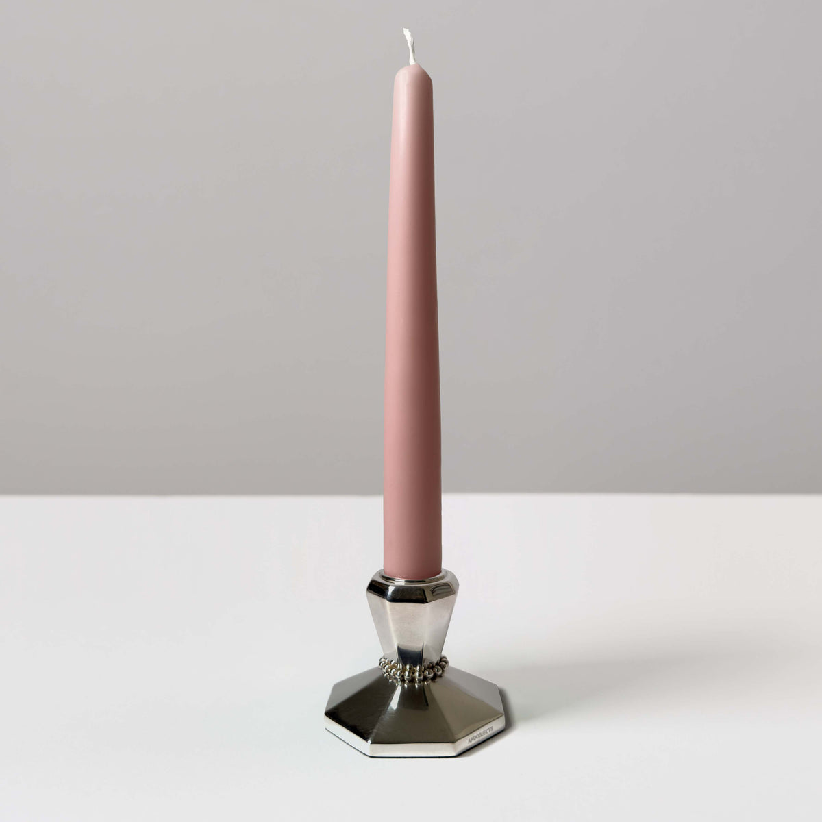 A single silver candle holder with pink taper