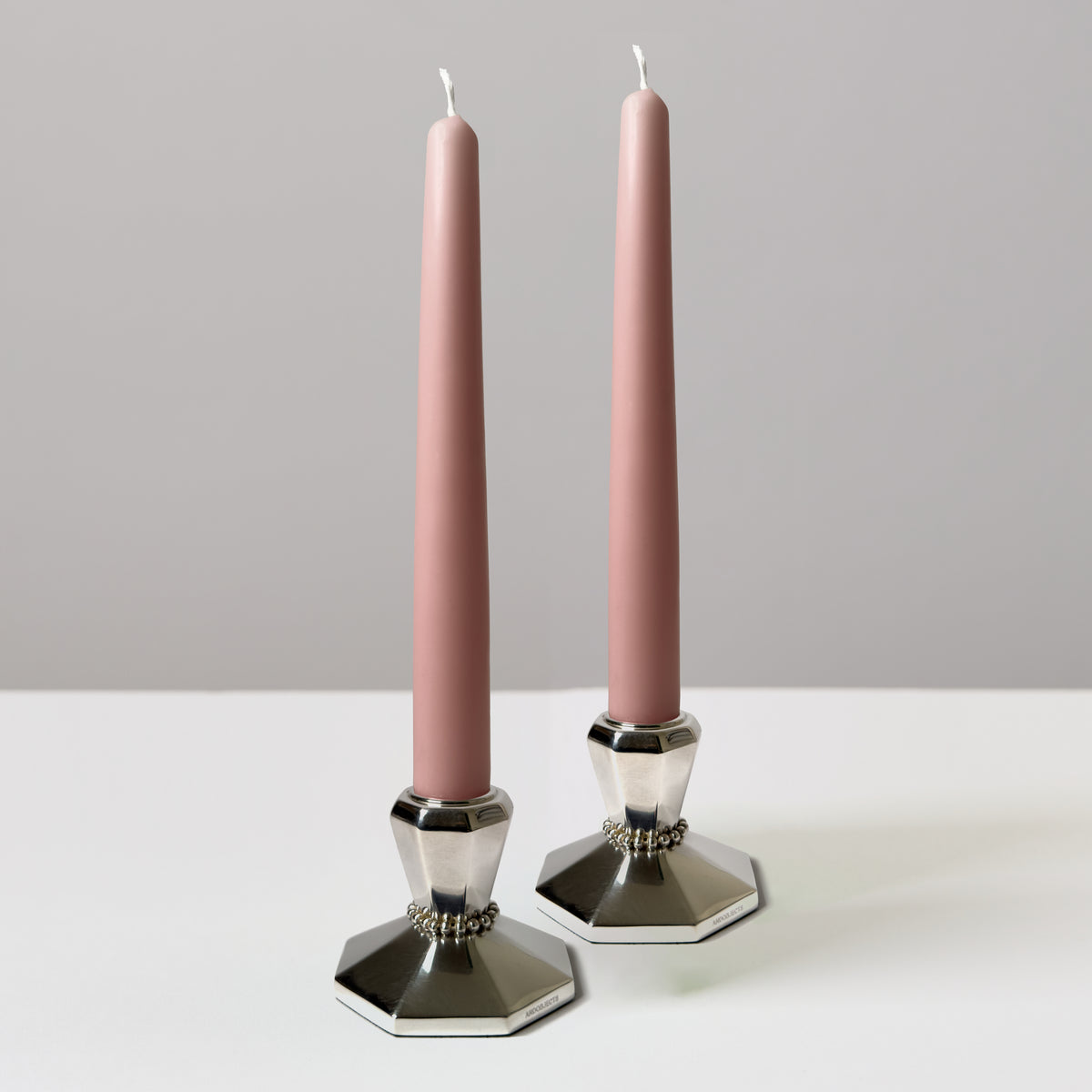 A pair of silver candle holders with pink tapers